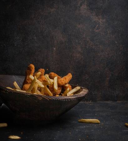 Side vew chicken nuggets with french fries in wooden plate on stone background Side vew chicken nuggets with french fries in wooden plate on stone background